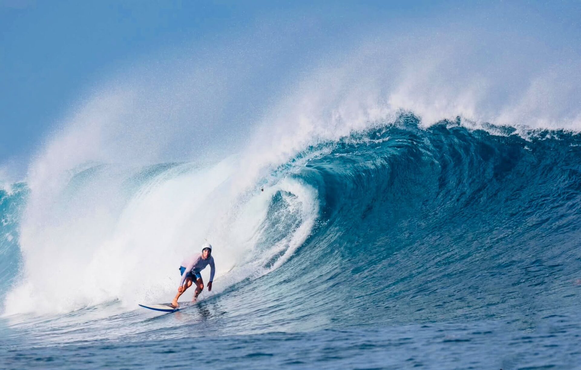 Surfer riding through a large blue barreling wave