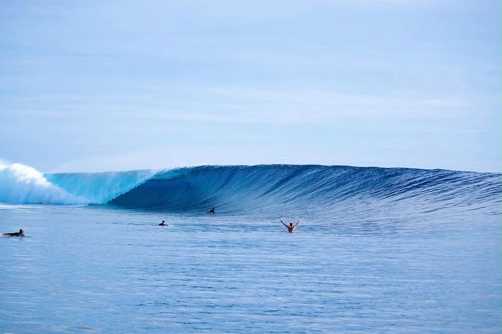 Surfers paddling out to a perfect empty barreling wave